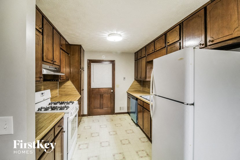 A kitchen with a white fridge and wooden cabinets.