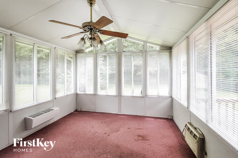 A room with a ceiling fan and windows covered with blinds.