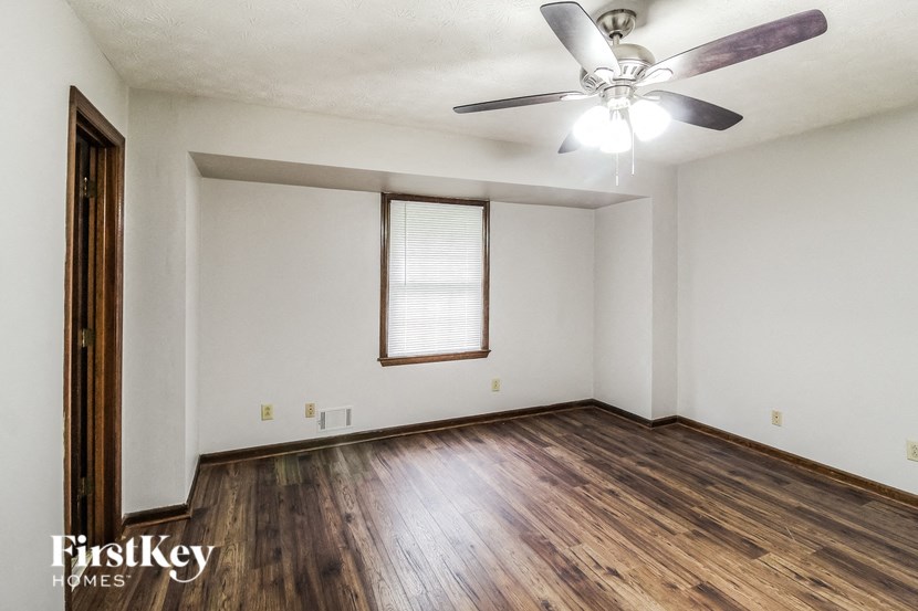 A room with a ceiling fan and wooden floors.