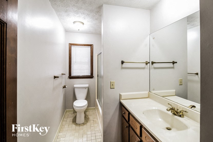 A bathroom with a toilet, sink and mirror.