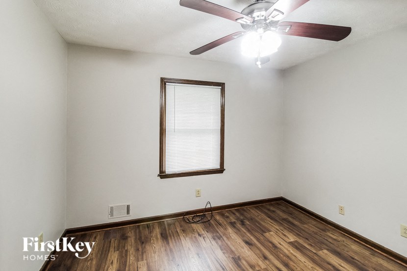 A room with a ceiling fan and wooden flooring.