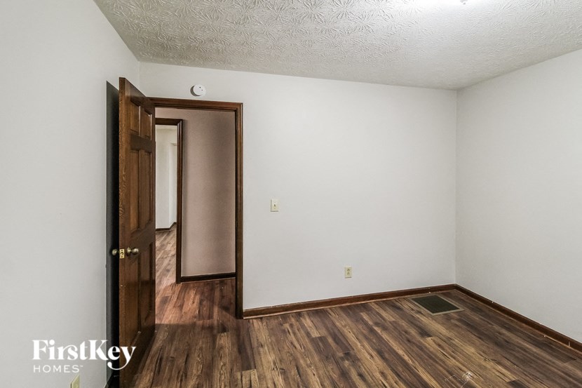 A room with a wooden floor and a door leading to another room.