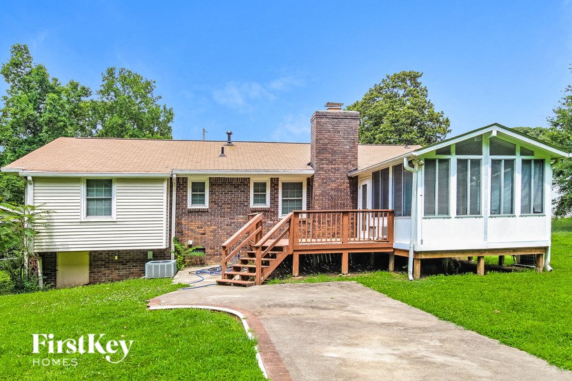 A house with a green house extension and a wooden deck.