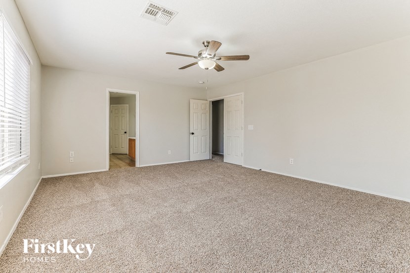 a spacious living room with carpet and a ceiling fan