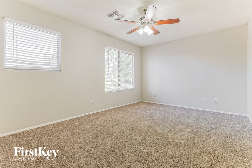 the spacious living room of a home with carpet and a ceiling fan
