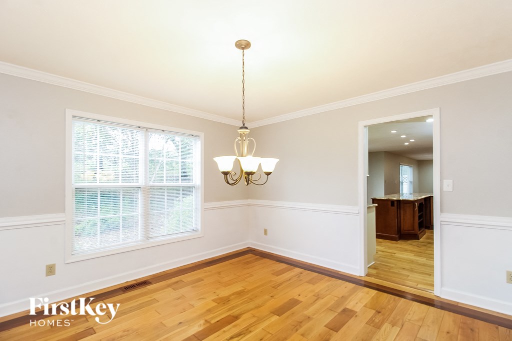 an empty dining room with hardwood floors and a chandelier
