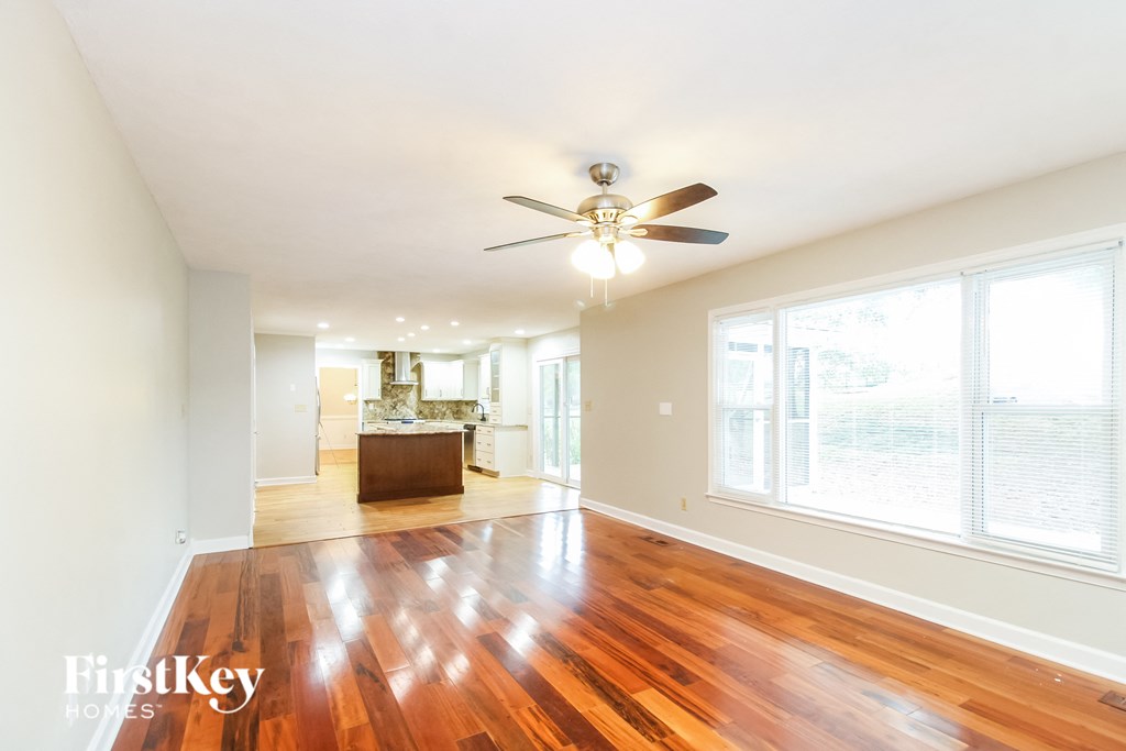 an empty living room with wood floors and a ceiling fan