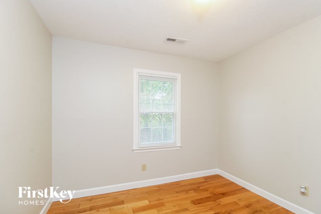 a bedroom with wood floors and white walls and a window