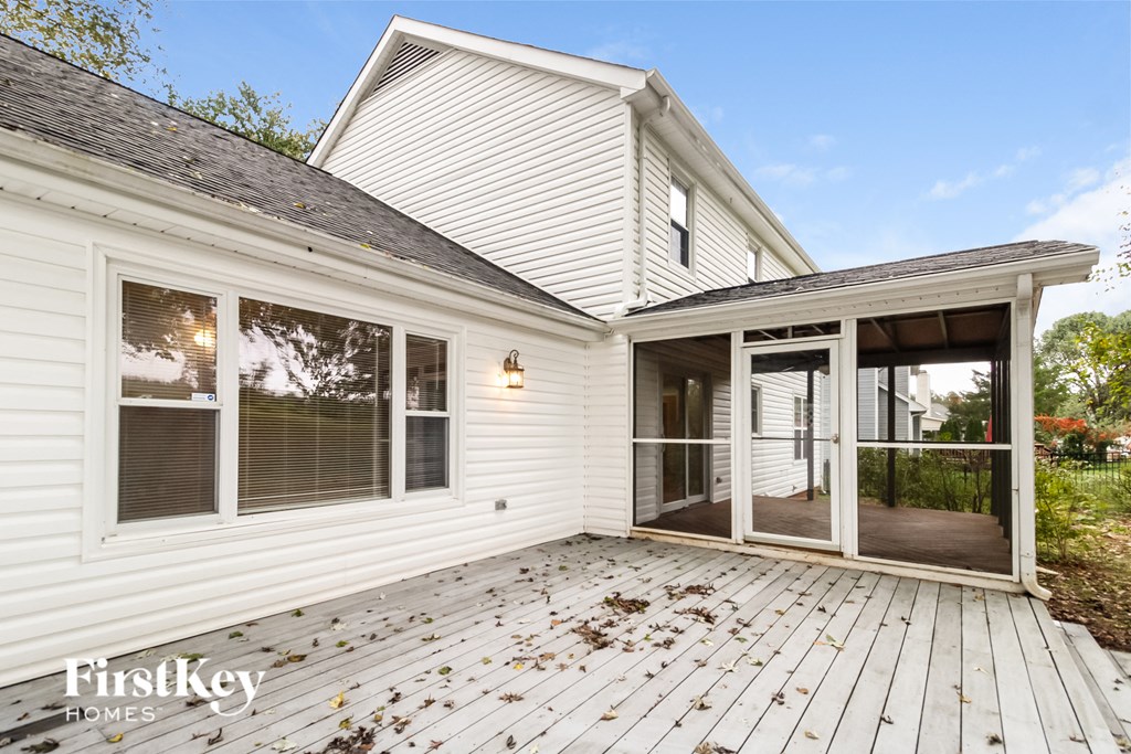 the back deck of a white house with a porch and glass doors