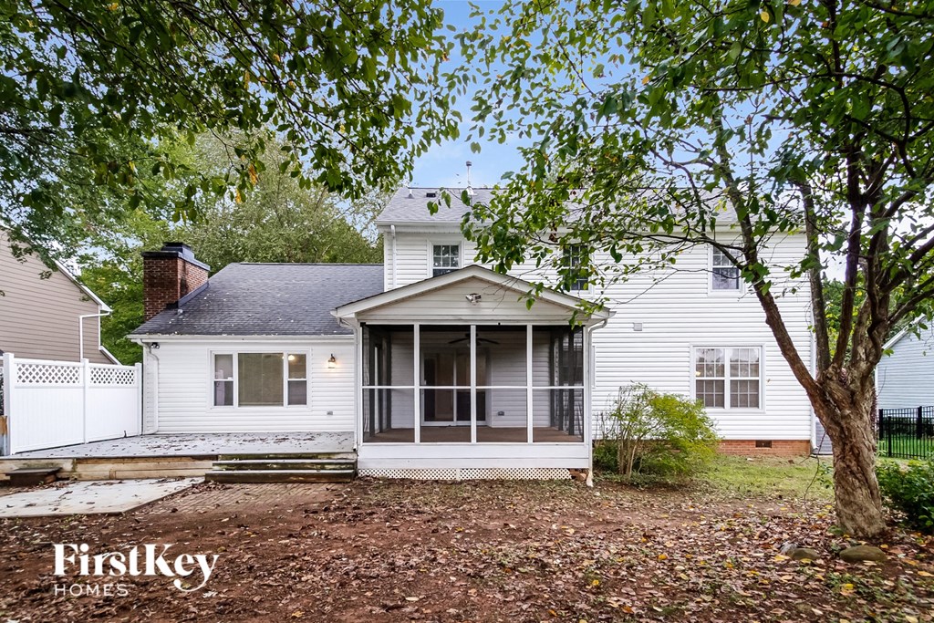 a small white house with a porch and a tree