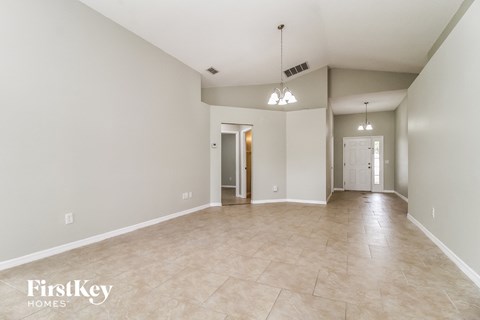 an empty living room and hallway with tile floors and white walls