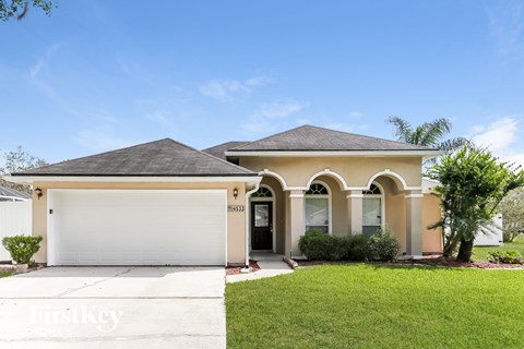 a beige house with a garage and a lawn