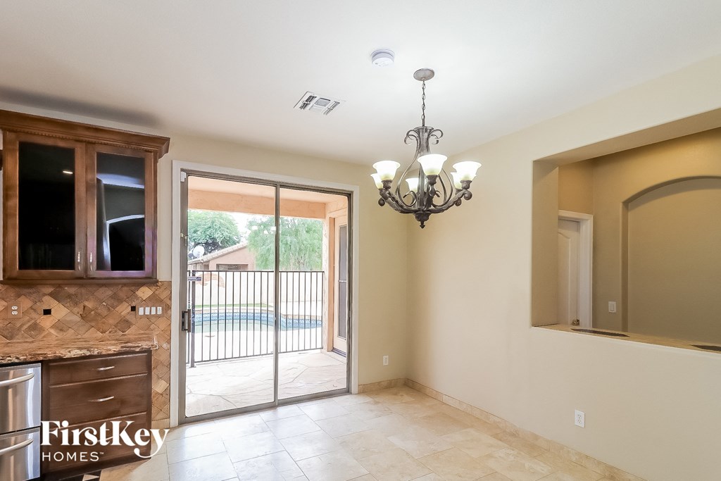 A chandelier hangs over a kitchen island with a sink and a window.