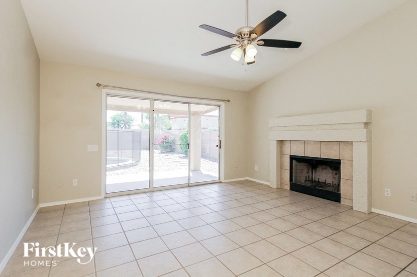 an empty living room with a fireplace and a ceiling fan