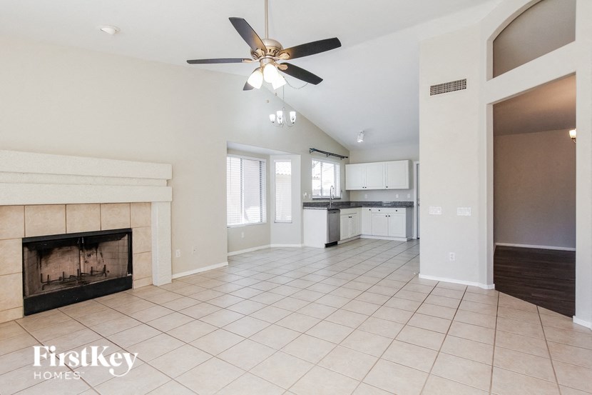 an empty living room with a fireplace and a ceiling fan