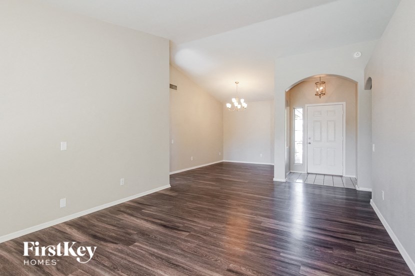 the spacious living room and dining room with white walls and wood flooring