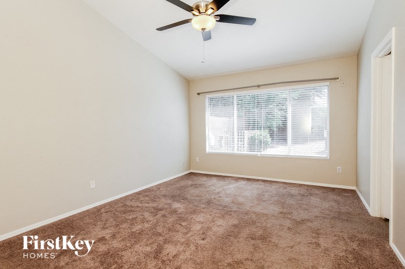 an empty room with a window and a ceiling fan
