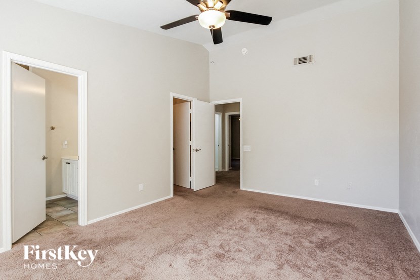 an empty living room with carpet and a ceiling fan