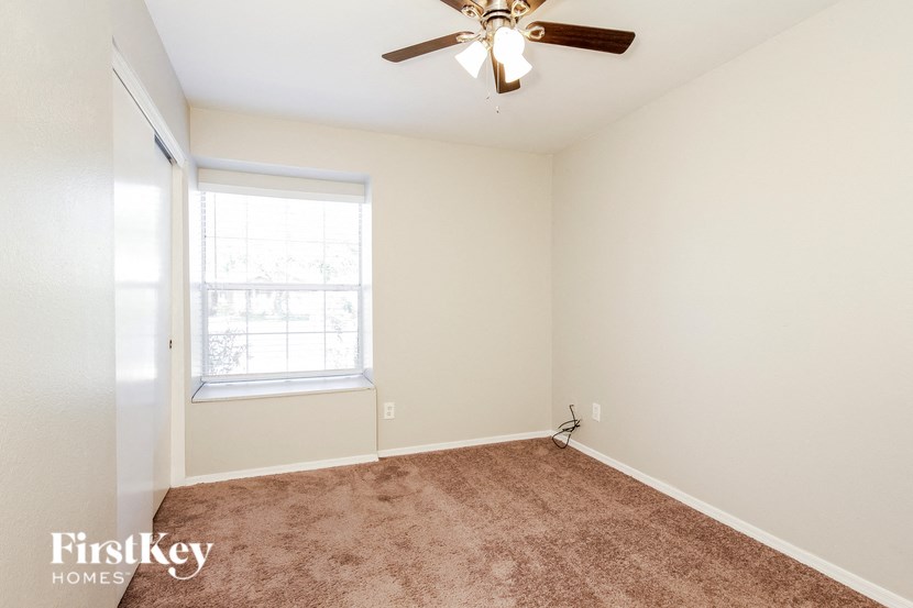 an empty room with a ceiling fan and a window