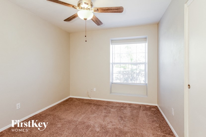 an empty room with a ceiling fan and a window