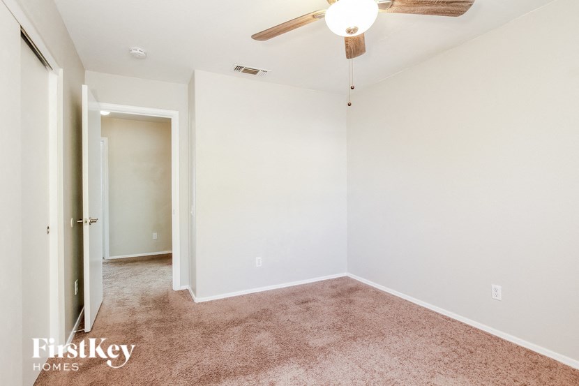 a bedroom with white walls and carpet and a ceiling fan