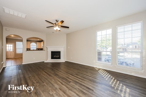 A spacious living room with a fireplace and a ceiling fan.