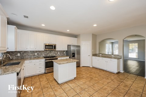 A kitchen with white cabinets and a stone backsplash.