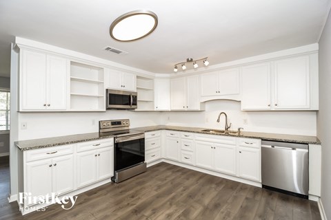 a white kitchen with stainless steel appliances and white cabinets