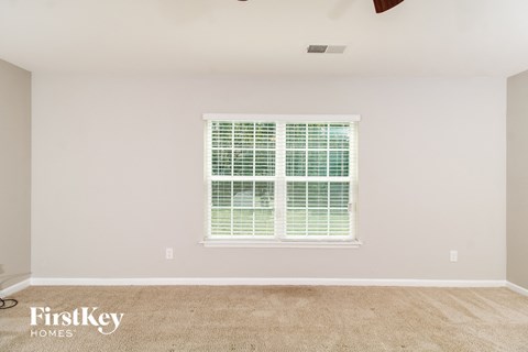 A room with a window covered in blinds and a carpet on the floor.