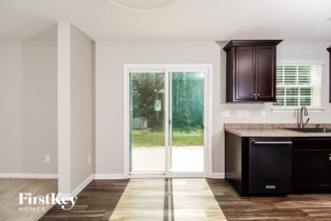 A kitchen with a black dishwasher and brown cabinets.