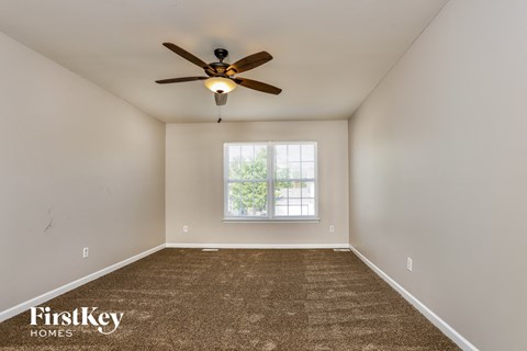 the master bedroom has a carpeted floor and a ceiling fan