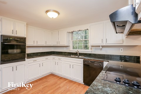 A kitchen with white cabinets and a black stove top oven.