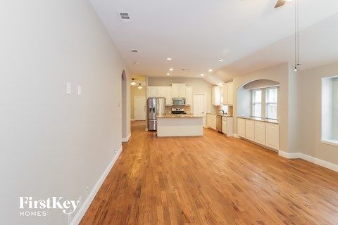A spacious kitchen with wooden floors and white walls.