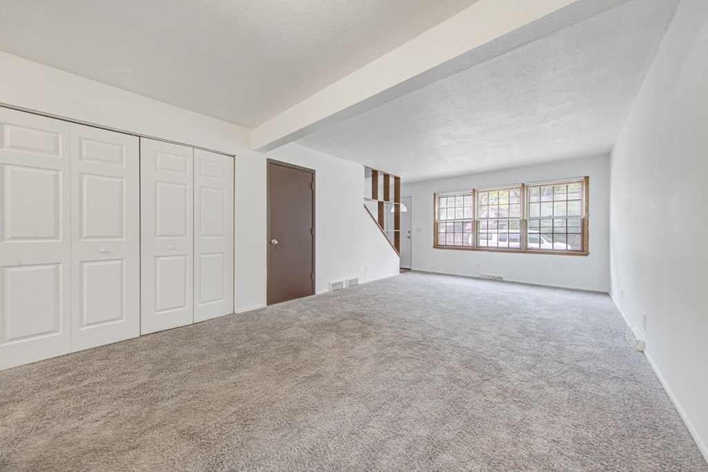 an empty living room with white walls and a window