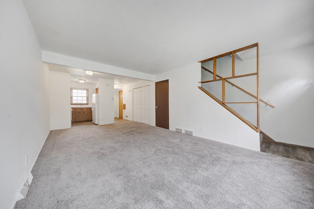the living room and dining room of an empty home with white walls and carpeting