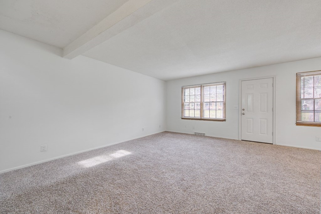 an empty living room with white walls and a white door and window
