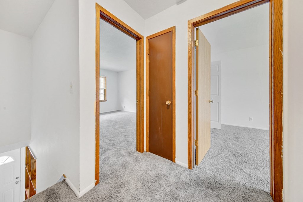 a bedroom with three doors and a carpeted floor