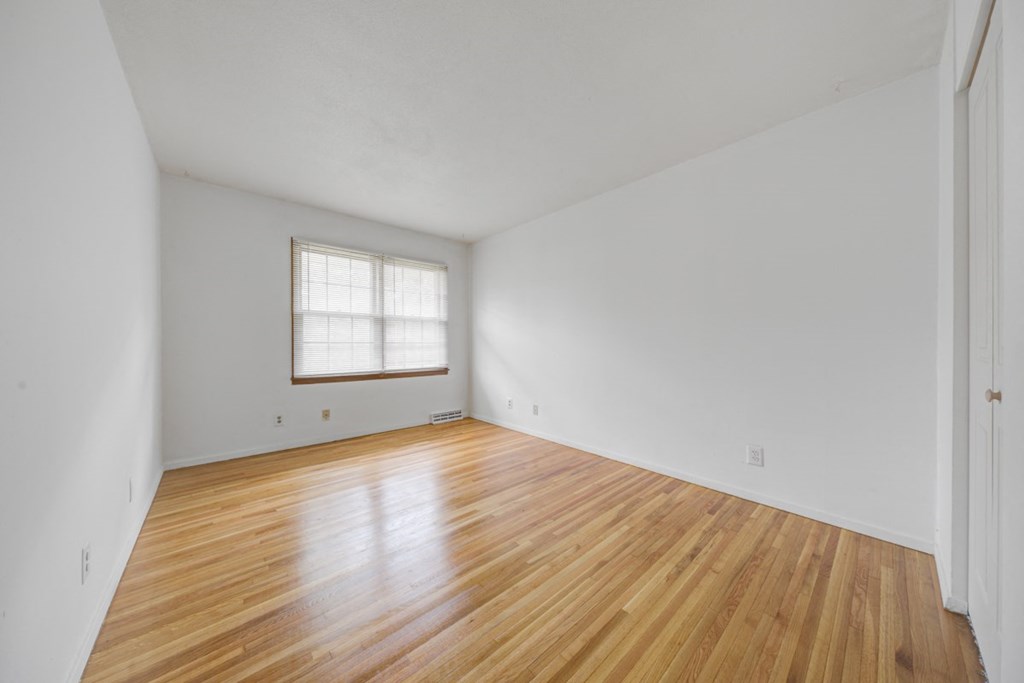 the living room of an empty house with wood floors and a window