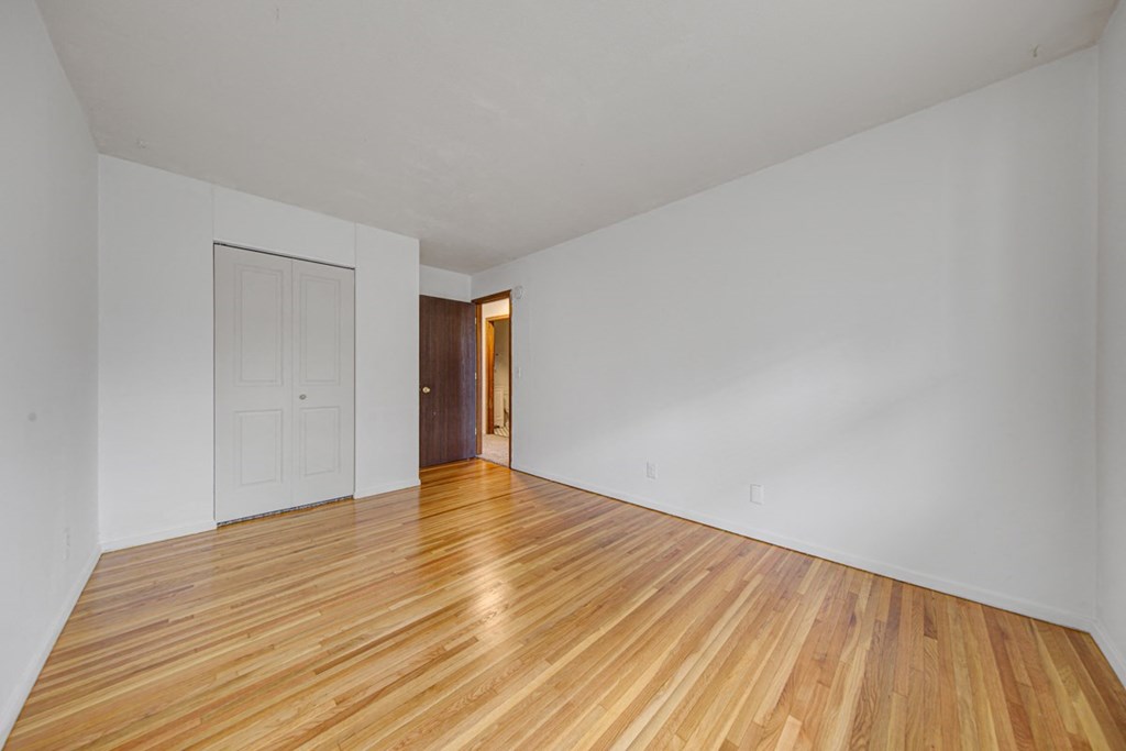 the living room and dining room of an apartment with wood floors and white walls