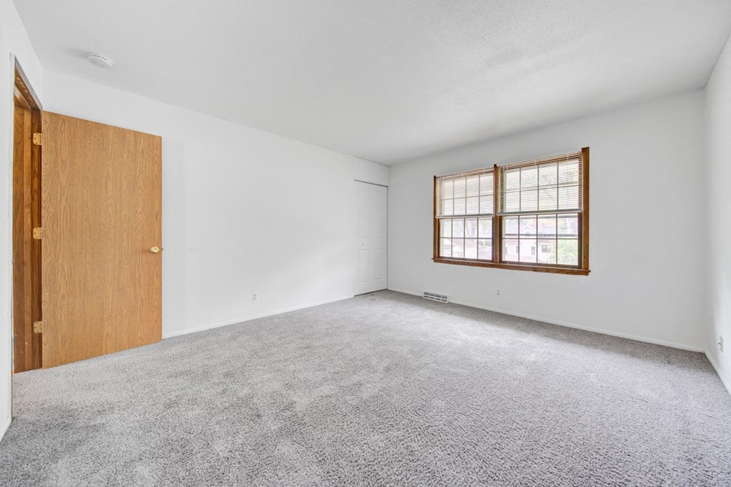 an empty room with white walls and a wooden door and window