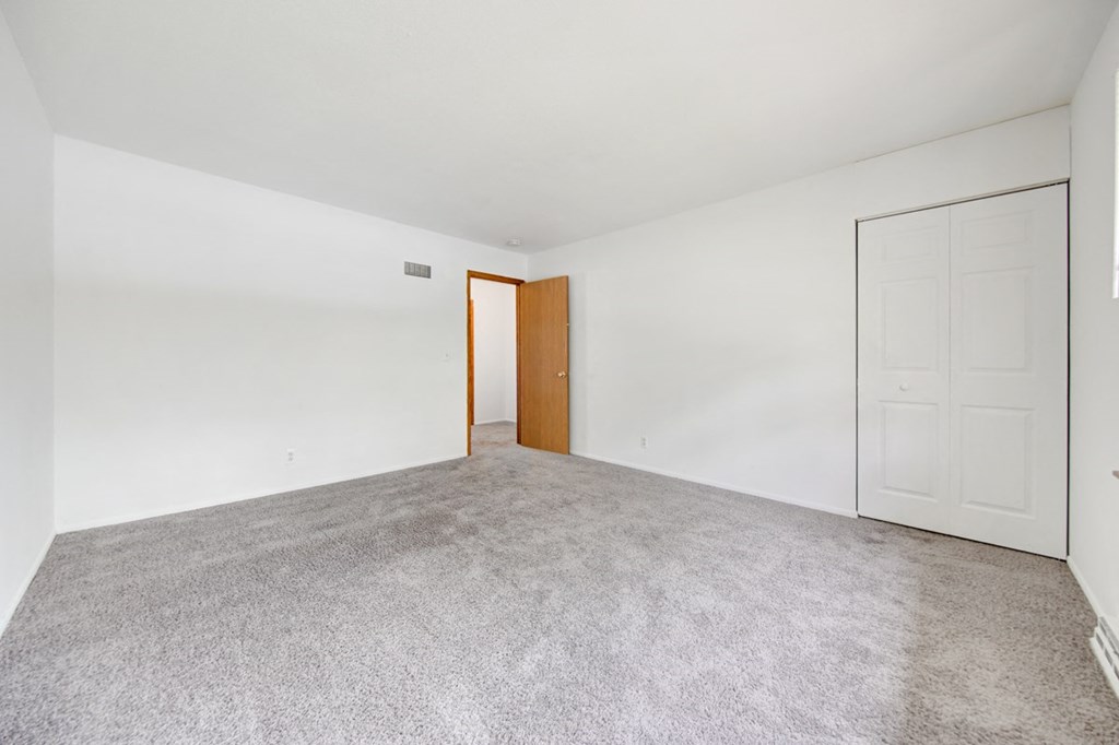 a bedroom with a carpeted floor and a door to a closet