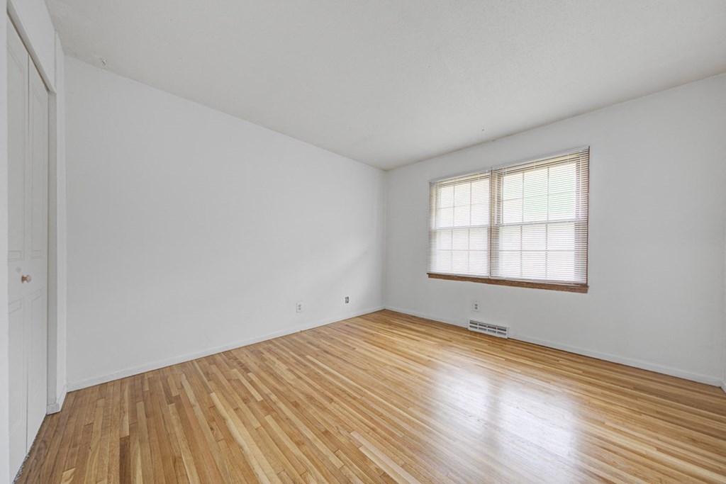 the living room of an empty house with wood floors and a window