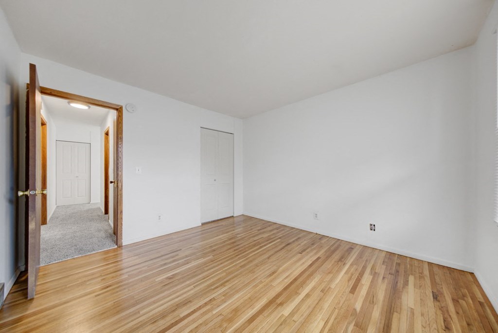 a living room with white walls and wood floors     and a door