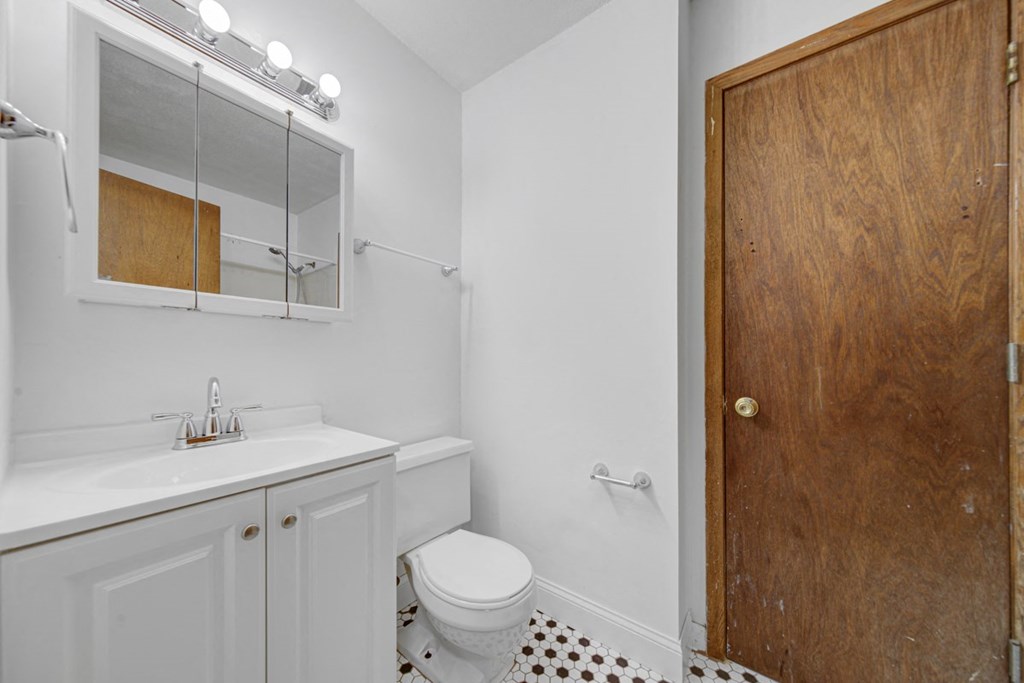 a white bathroom with a wooden door and a toilet