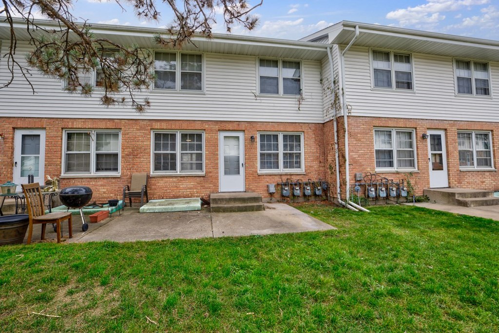 a brick building with a patio and a grill in front of it
