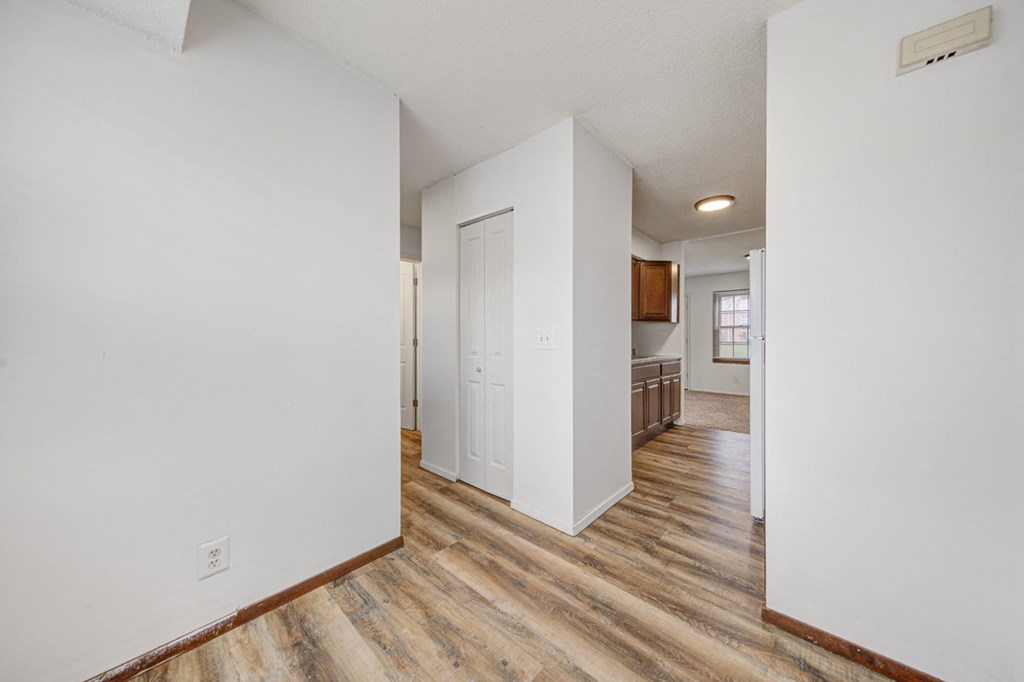 the living room and dining room of an apartment with white walls and wood floors