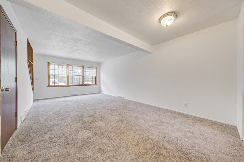an empty living room with carpet and a window