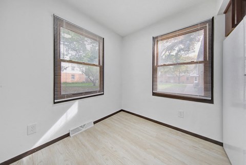the living room of a house with two windows and wood flooring