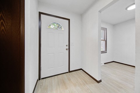 an empty living room with a white door and a window