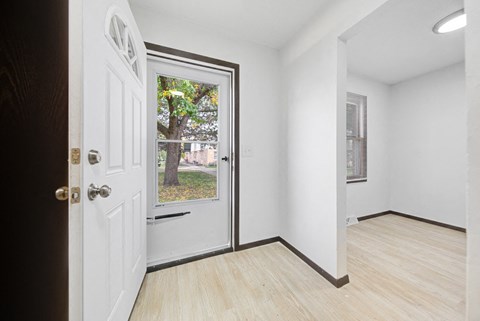 an empty room with a white door and a window